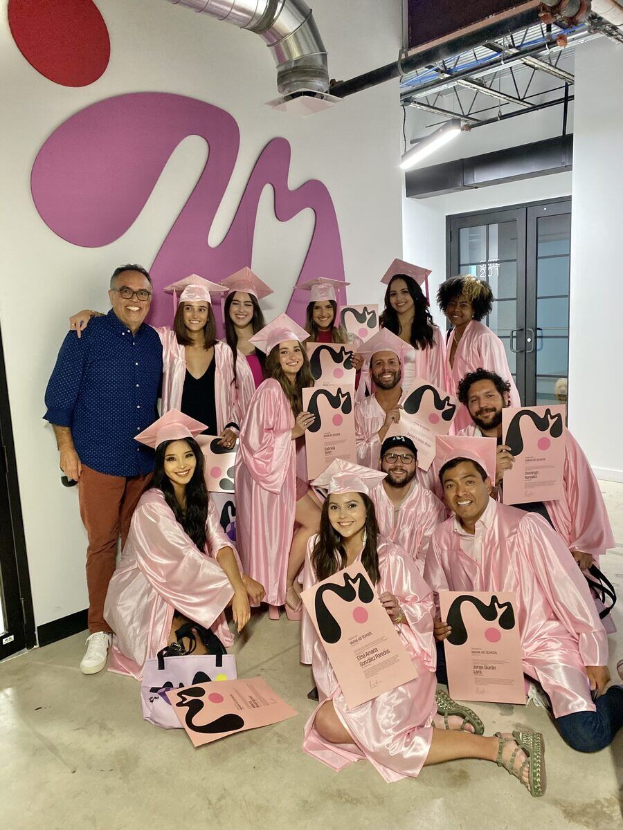 A diverse group of individuals proudly wearing pink graduation robes, celebrating their academic achievements together.